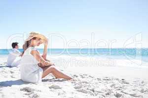Brunette sitting in the sand and looking at the sea