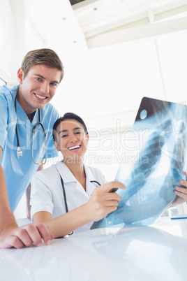 Happy doctors looking at camera and holding X-ray