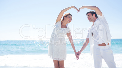 Happy couple forming heart shape with their hands