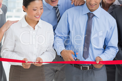 Business man cutting red strip