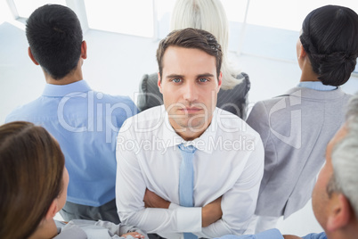 Unhappy businessman looking at camera with his colleague around