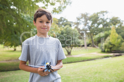 Boy looking at camera and holding a toy plane at park
