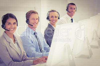 Business team working on computers and wearing headsets