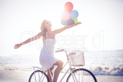 Beautiful blonde on bike ride holding balloons