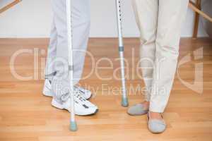 Doctor helping her patient walking with crutch