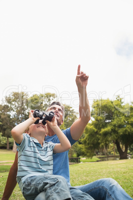 Father and his son using binocular in the park