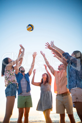 Happy friends throwing volleyball