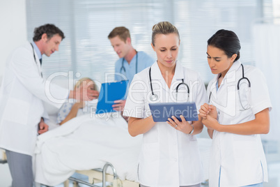 Doctors looking at clipboard while theirs colleagues speaks with