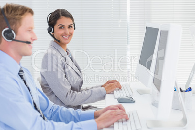 Business team working on computers and wearing headsets