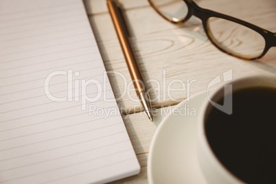 Empty notepad with reading glasses and cup of coffee