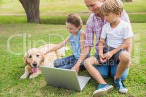 Happy family with their dog using laptop
