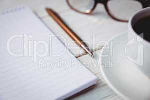 Empty notepad with reading glasses and cup of coffee
