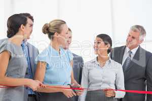 Happy business team cutting red ribbon