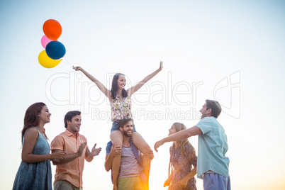 Happy friends dancing on the sand with balloon