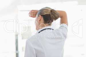 Wear view of confident female doctor looking through windows