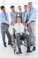 Business people supporting their colleague in wheelchair