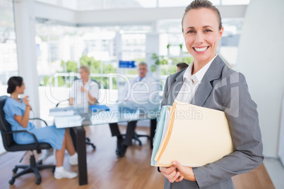 Smiling businesswoman holding files and looking at camera