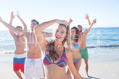 Happy friends dancing on the sand