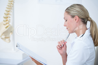 Doctor writing on clipboard at her desk