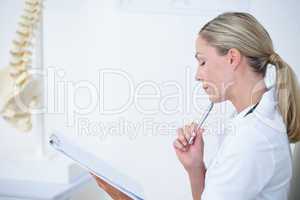 Doctor writing on clipboard at her desk