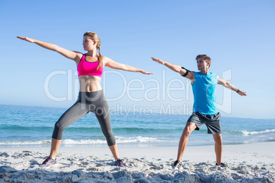 Happy couple doing yoga beside the water