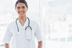 Happy doctor looking at camera beside windows