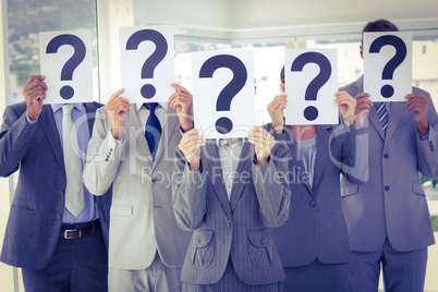 Business team holding question marks over face