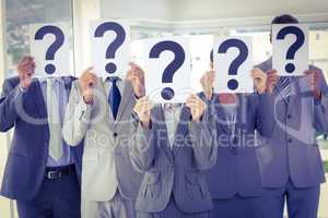 Business team holding question marks over face