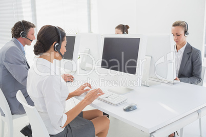 Business team working on computers and wearing headsets