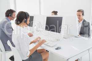 Business team working on computers and wearing headsets