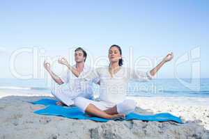 Happy couple doing yoga beside the water