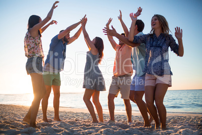 Happy friends dancing on the sand