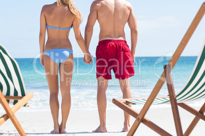 Happy couple holding hands and looking at the sea