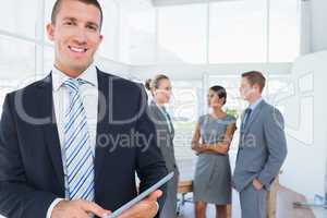 Businessman using tablet with colleagues behind him