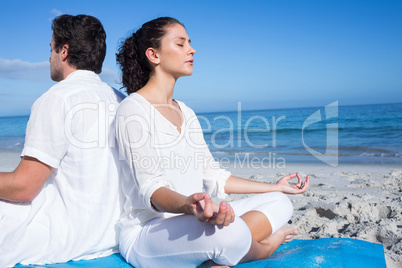 Happy couple doing yoga beside the water