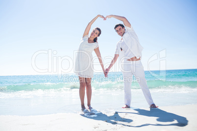 Happy couple forming heart shape with their hands