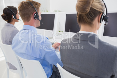 Business team working on computers and wearing headsets