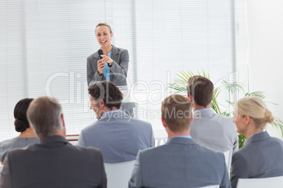 Pretty businesswoman talking in microphone during conference