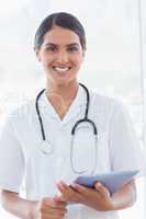 Happy doctor holding clipboard and smiling at camera