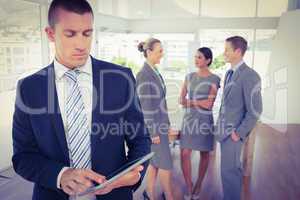 Businessman using tablet with colleagues behind him