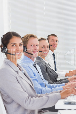 Business team working on computers and wearing headsets