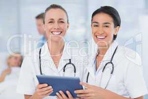 Happy doctors looking at clipboard while theirs colleagues speak