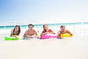 Happy friends lying on inflatable mattress above the water