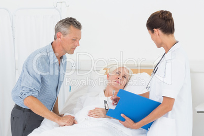 Doctor explaining report to female patient and husband