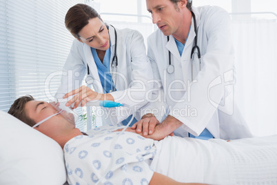 Worried doctors doing heart massage and holding oxygen mask