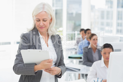 Businesswoman checking her clipboard while team work using compu