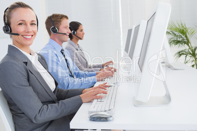 Business team working on computers and wearing headsets