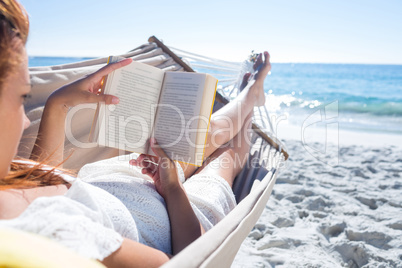 Brunette reading a book while relaxing in the hammock