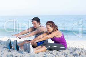 Happy couple stretching together beside the water