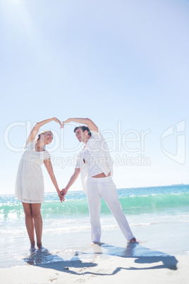 Happy couple forming heart shape with their hands